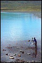 Large format photographer with tripod on the shores of Turquoise Lake. Lake Clark National Park, Alaska