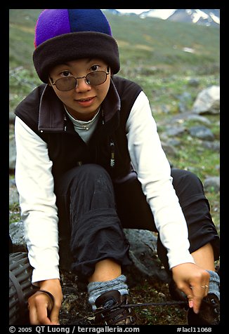 Woman backpacker putting back boots after a stream crossing. Lake Clark National Park, Alaska (color)