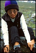 Woman backpacker putting back boots after a stream crossing. Lake Clark National Park, Alaska (color)