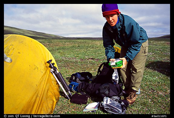 Photographer unpacking boxes of film from backpack. Lake Clark National Park, Alaska (color)