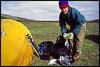 Photographer unpacking boxes of film from backpack. Lake Clark National Park, Alaska (color)