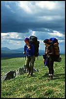 Two women backpackers pausing in the tundra with alpine flowers in the background. Lake Clark National Park, Alaska (color)