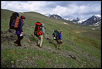 Backpackers with big packs going down a slope. Lake Clark National Park, Alaska