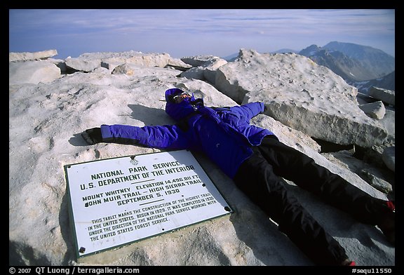 Hiker laying exhausted on Mt Whitney summit sign. Sequoia National Park, California