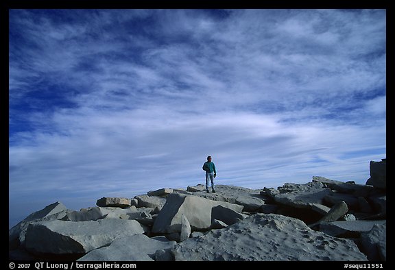 Hiker standing on flat rocks on top of Mt Whitney summit. California (color)