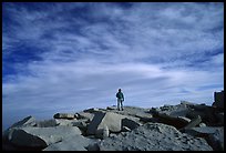 Hiker standing on flat rocks on top of Mt Whitney summit. California