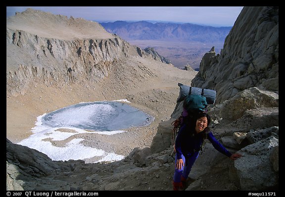 Woman with backpack pausing on steep terrain above Iceberg Lake. California (color)