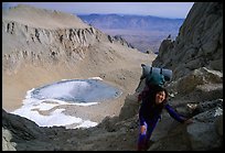 Woman with backpack pausing on steep terrain above Iceberg Lake. California ( color)