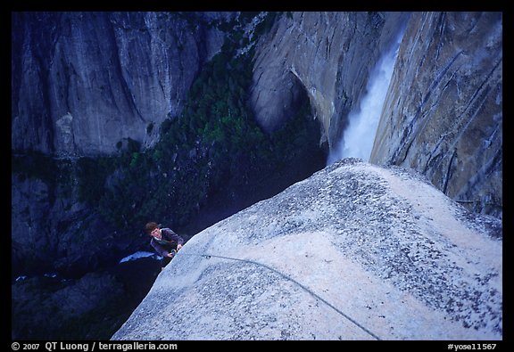 Climber near the top of Lost Arrow spire with Yosemite Falls behind. Yosemite National Park, California (color)