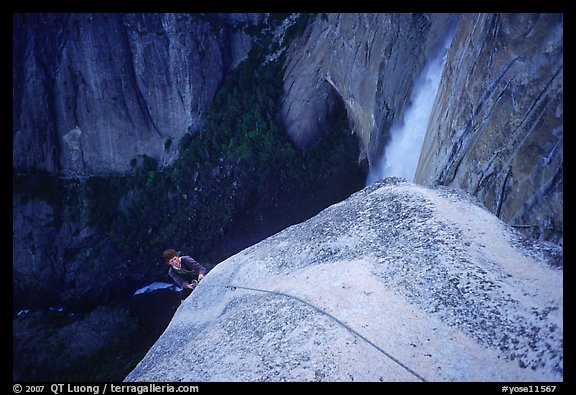 Climber near the top of Lost Arrow spire with Yosemite Falls behind. Yosemite National Park, California