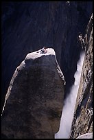 Climber resting on top of Lost Arrow spire with Yosemite Falls behind. Yosemite National Park, California (color)