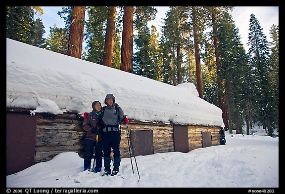 Skiing couple in front of the Mariposa Grove Museum in winter. Yosemite National Park, California