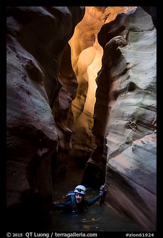 Woman wades in chest deep water of flooded slot canyon, Pine Creek Canyon. Zion National Park, Utah (color)