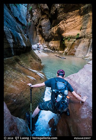 Hiker straddling stream in Orderville Canyon. Zion National Park, Utah (color)