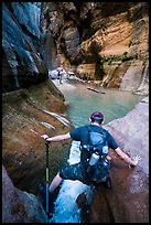 Hiker straddling stream in Orderville Canyon. Zion National Park, Utah ( color)