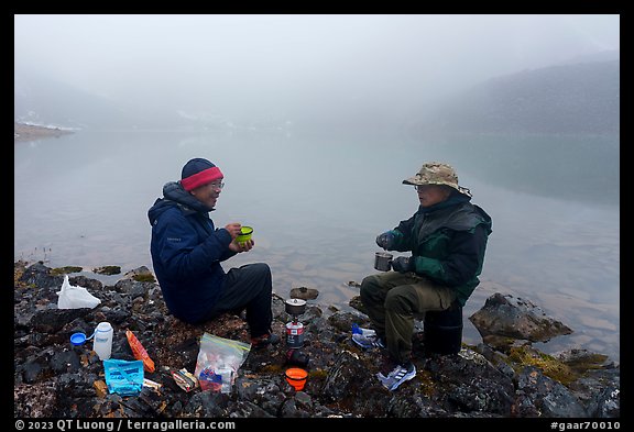 Backpackers eating on shore of foggy lake. Gates of the Arctic National Park (color)