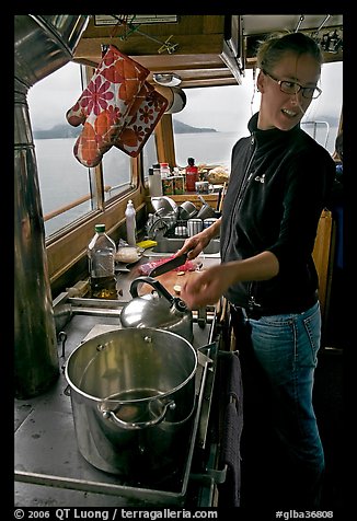 Chef cooking aboard small boat. Glacier Bay National Park, Alaska, USA.