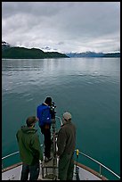 Film crew working on the bow of a small boat. Glacier Bay National Park, Alaska, USA.