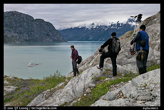 Film crew carrying a motion picture camera down rocky slopes. Glacier Bay National Park, Alaska, USA.