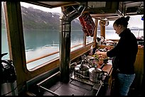 Chef preparing sadad in the main cabin of the Kahsteen. Glacier Bay National Park, Alaska, USA. (color)