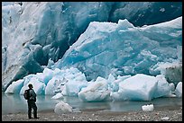 Hiker looking at ice wall at the front of Reid Glacier. Glacier Bay National Park, Alaska, USA.