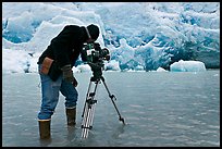 Cameraman standing in water at the base of Reid Glacier. Glacier Bay National Park, Alaska, USA.