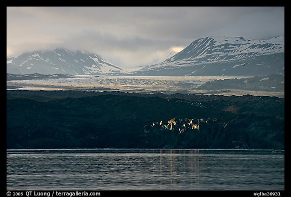 Last sunrays catched by the moraine-covered face of Grand Pacific Glacier. Glacier Bay National Park, Alaska, USA.