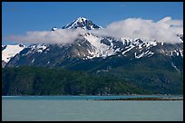 Snowy peaks and clouds raising above turquoise waters in sunny weather. Glacier Bay National Park, Alaska, USA.