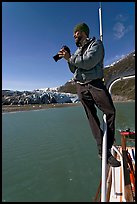 Photographer perched on boat in Reid Inlet. Glacier Bay National Park, Alaska, USA.
