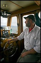 Captain steering boat using navigation instruments. Glacier Bay National Park, Alaska, USA. (color)