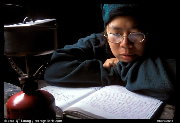 Backpacker reads log in abandonned geological survey cabin, Valley of Ten Thousand smokes. Katmai National Park, Alaska (color)