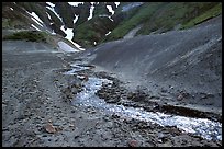 Stream flows from verdant hills into  barren valley floor. Katmai National Park ( color)