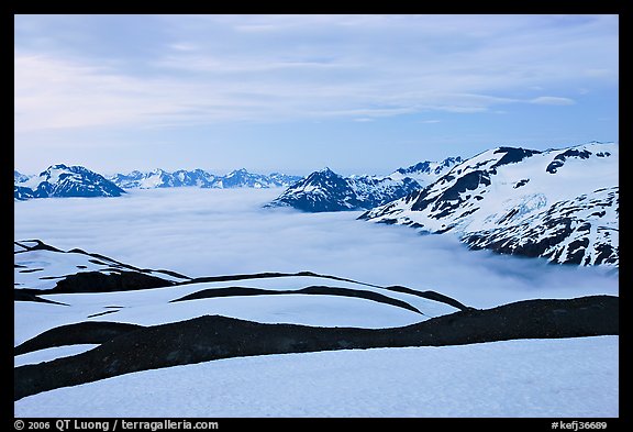 Dark bands of freshly uncovered terrain, snow, and low clouds, dusk. Kenai Fjords National Park, Alaska, USA.