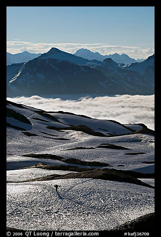 Mountains and sea of clouds, hiker on snow-covered trail. Kenai Fjords National Park, Alaska, USA.