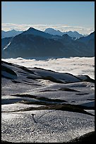 Mountains and sea of clouds, hiker on snow-covered trail. Kenai Fjords National Park, Alaska, USA. (color)