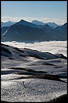 Mountains and sea of clouds, hiker on snow-covered trail. Kenai Fjords National Park, Alaska, USA.