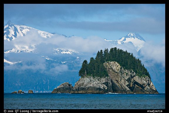 Rocky islet and snowy peaks, Aialik Bay. Kenai Fjords National Park, Alaska, USA.