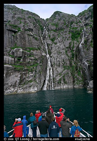 Passengers looking at waterfalls from  bow of tour boat, Cataract Cove. Kenai Fjords National Park, Alaska, USA.