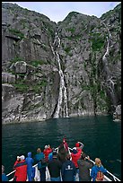 Passengers looking at waterfalls from  bow of tour boat, Cataract Cove. Kenai Fjords National Park, Alaska, USA.