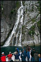 Passengers look at waterfall from tour boat, Cataract Cove, Northwestern Fjord. Kenai Fjords National Park, Alaska, USA. (color)