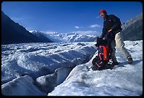 Hiker reaching into backpack on Root glacier. Wrangell-St Elias National Park, Alaska, USA.