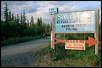 Sign and couple walking on McCarthy road near Silver Lake. Wrangell-St Elias National Park, Alaska, USA. (color)