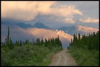 Gravel road leading to mountains lit by sunset light. Wrangell-St Elias National Park, Alaska, USA. (color)