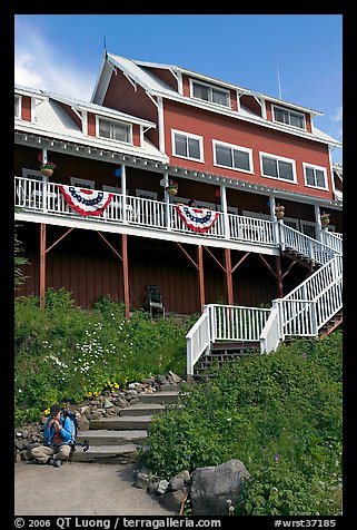 Hiker sitting on steps of Kennicott Lodge. Wrangell-St Elias National Park, Alaska, USA.