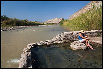 Tourist sitting in hot springs next to river. Big Bend National Park, Texas, USA.