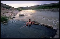 Visitor relaxes in hot springs next to Rio Grande. Big Bend National Park, Texas, USA.