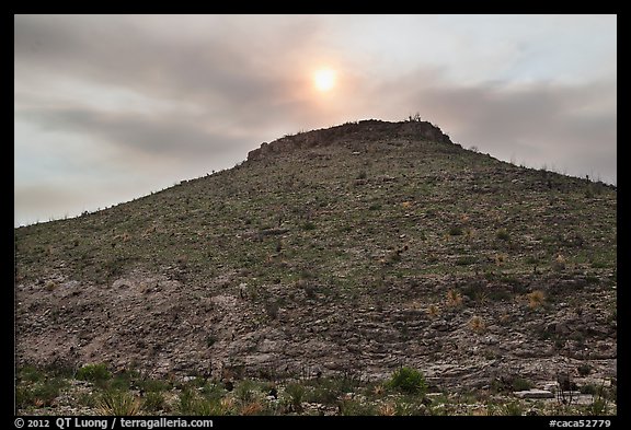 Hill with burned vegetation and sun shining through smoke. Carlsbad Caverns National Park, New Mexico, USA.