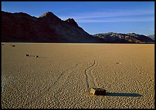 Tracks, moving stone on Racetrack playa and Ubehebe Peak, late afternoon. Death Valley National Park, California, USA.