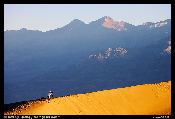 Photographer on dune ridge at sunrise. Death Valley National Park, California, USA.