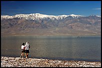 Couple watches the dragon in ephemeral lake. Death Valley National Park, California, USA. (color)